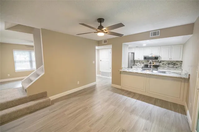a kitchen with stainless steel appliances granite countertop a stove a sink and white cabinets with wooden floor