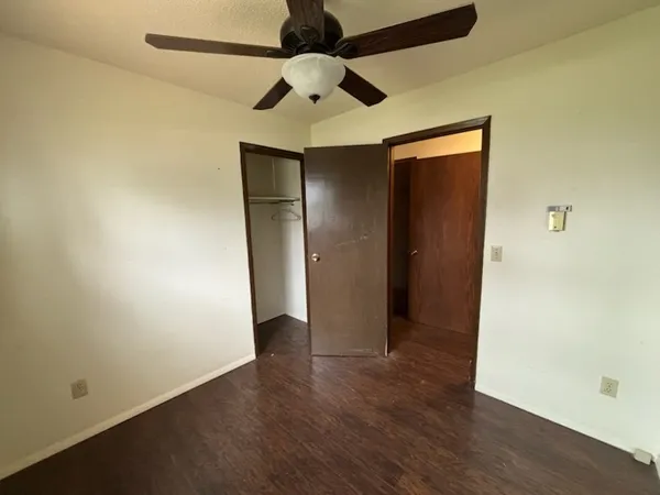an empty room with wooden floor a ceiling fan and closet area