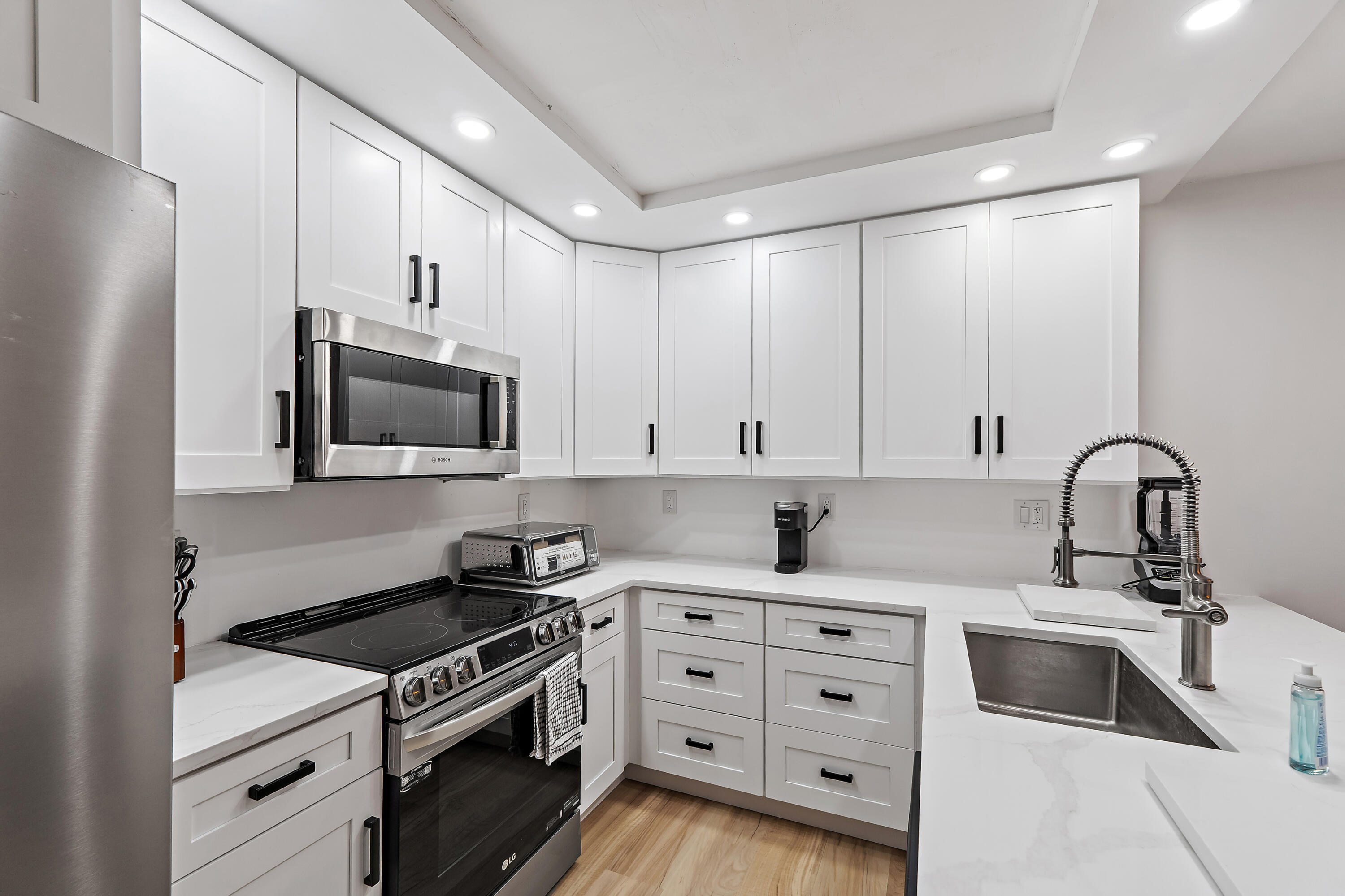 3052 30th Court Jupiter, FL 33477 - Photo 21 of 45 a kitchen with white cabinets and stainless steel appliances