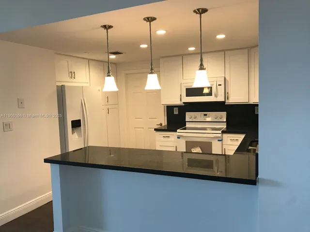 a large kitchen with stainless steel appliances granite countertop a sink a microwave a refrigerator and a stove