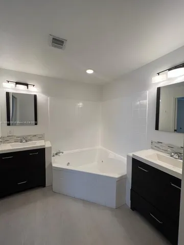 a bathroom with a bathtub a double vanity sink and mirror