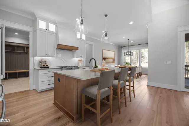 a large kitchen with stainless steel appliances granite countertop a large center island a stove a refrigerator and a view of living room