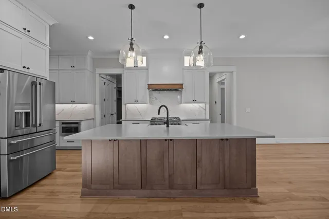 a kitchen with stainless steel appliances granite countertop a sink a stove and a wooden floors