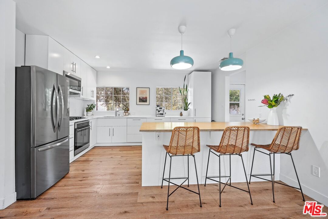 6926 Cedros Avenue Van Nuys, CA 91405 - Photo 11 of 26 a kitchen with stainless steel appliances kitchen island granite countertop a refrigerator and a stove top oven