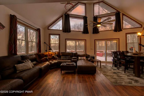 a living room with furniture two window and wooden floor