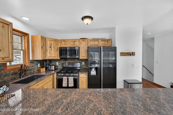 a kitchen with stainless steel appliances granite countertop a refrigerator a stove and a sink with wooden floor
