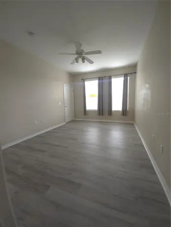 an empty room with wooden floor and windows
