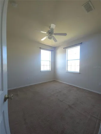 an empty room with windows and fan