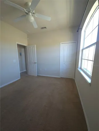 an empty room with windows and fan