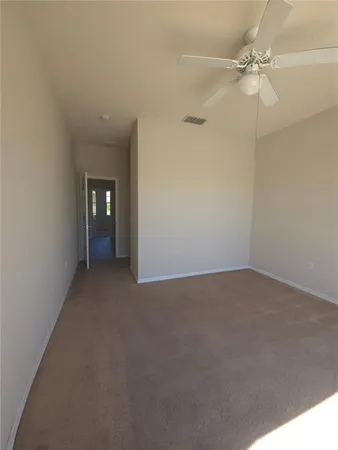 a view of an empty room with a ceiling fan and window