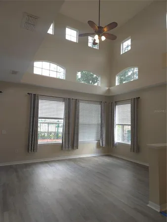 a view of an empty room with a window and wooden floor