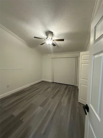an empty room with wooden floor ceiling fan and window