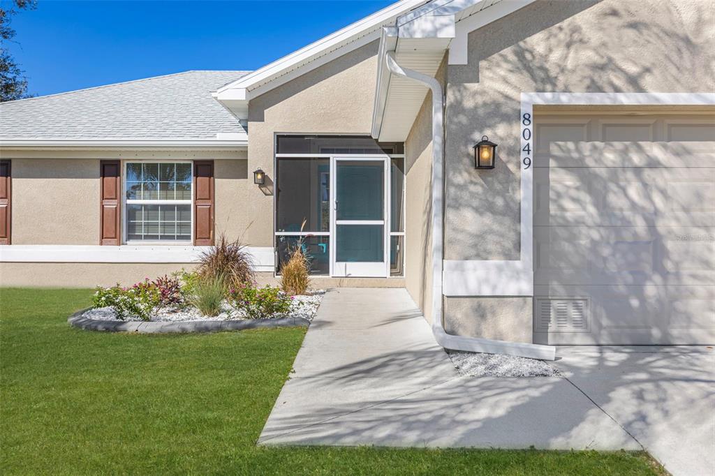 8049 Dimstead Street Port Charlotte, FL 33981 - Photo 2 of 39 a front view of a house with a garden and plants