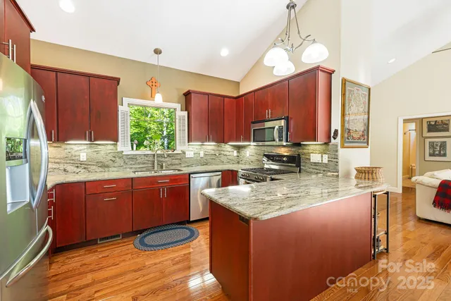 a kitchen with stainless steel appliances granite countertop wooden cabinets a stove a sink and a wooden floor