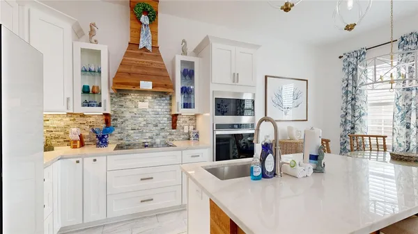 a kitchen with stainless steel appliances kitchen island granite countertop a refrigerator a stove and white cabinets with wooden floor