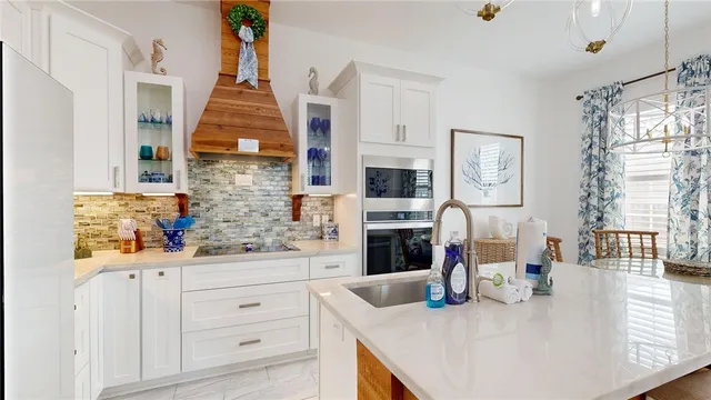 a kitchen with stainless steel appliances kitchen island granite countertop a refrigerator a stove and white cabinets with wooden floor