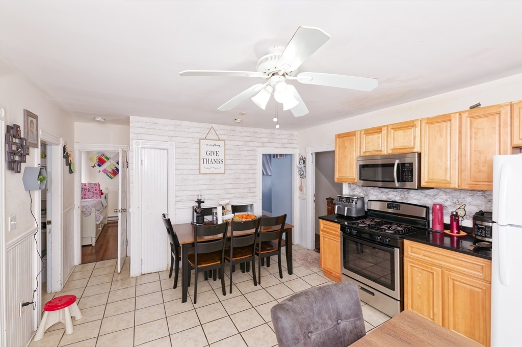 10 Rhubena Street Framingham, MA 01702 - Photo 8 of 30 a kitchen with stainless steel appliances granite countertop a stove top oven a sink a dining table and chairs with wooden floor
