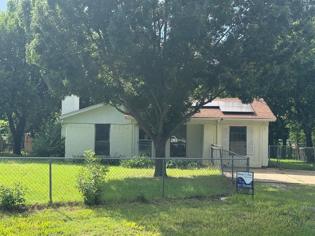 329 Walnut Avenue Azle, TX 76020 - Photo 1 of 6 Single-story residence featuring a chain-link fence, mature trees, and a paved driveway