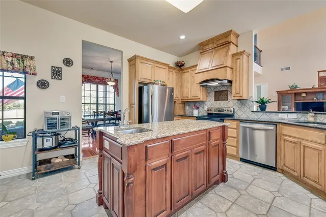 a kitchen with stainless steel appliances granite countertop a kitchen island a stove and a sink