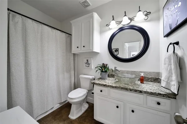 a bathroom with a granite countertop toilet sink and mirror