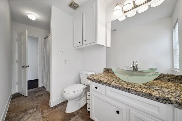 a bathroom with a granite countertop sink a toilet and a mirror