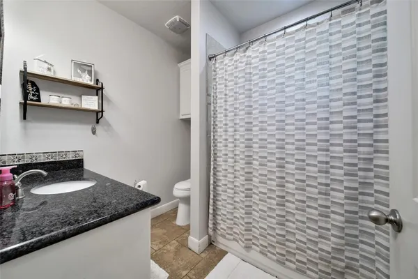 a bathroom with a granite countertop sink a toilet and a mirror
