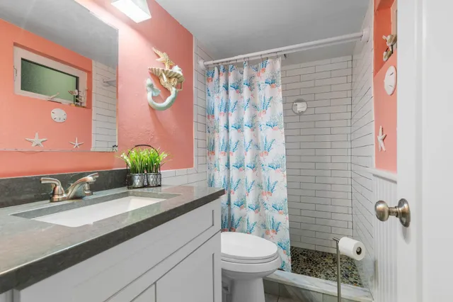 a bathroom with a granite countertop sink a toilet and shower