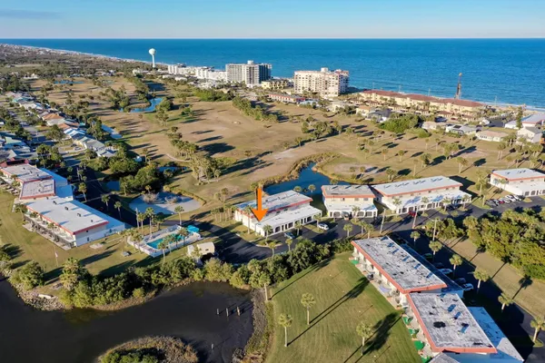 an aerial view of ocean and residential houses with outdoor space