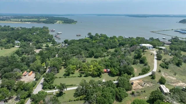 an aerial view of a houses with outdoor space and trees all around