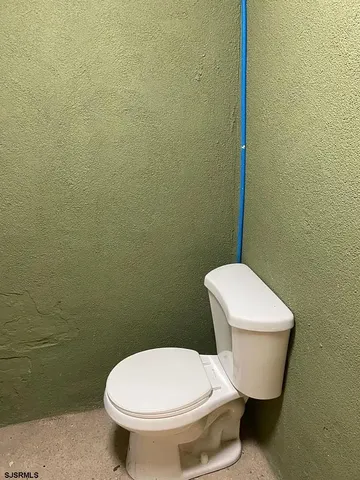 a white toilet sitting next to a white wall