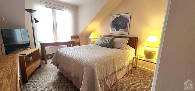 a bedroom with a bed and a flat tv screen on dresser