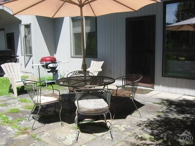 a view of a patio with table and chairs under an umbrella