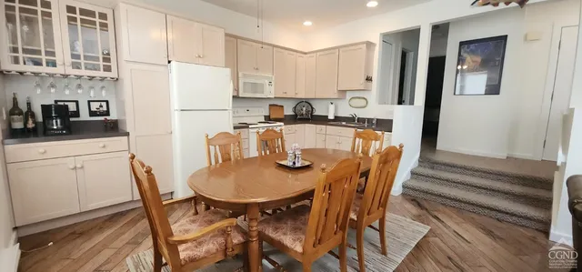 a kitchen with stainless steel appliances granite countertop a stove a refrigerator a table and chairs with wooden floor