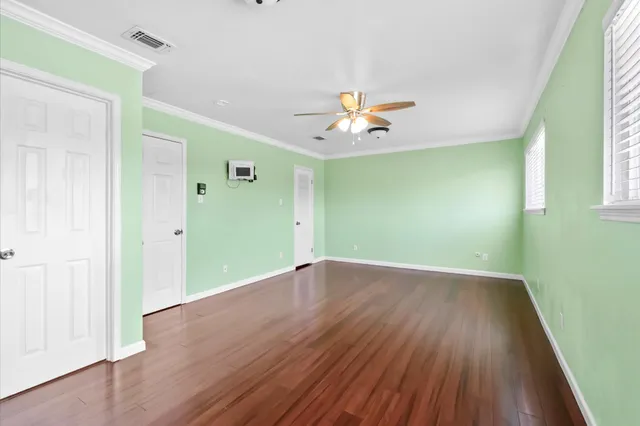 an empty room with wooden floor and windows
