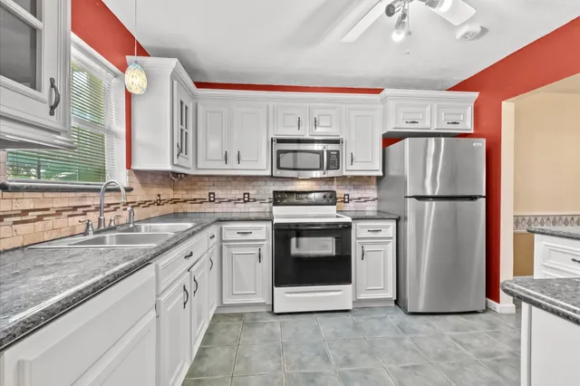 a kitchen with granite countertop a refrigerator oven a sink and dishwasher
