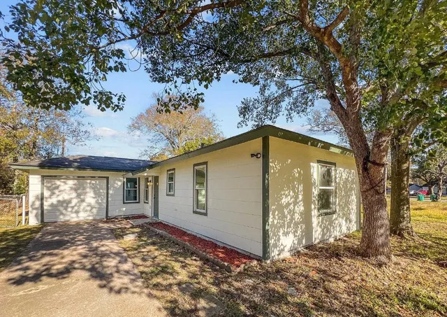 a view of a house with a large tree and a yard