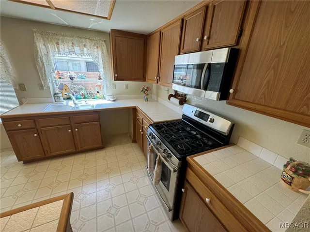 a kitchen with stainless steel appliances a refrigerator a sink a stove top oven a refrigerator and cabinets