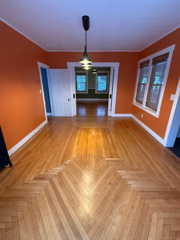a view of an empty room with window and wooden floor
