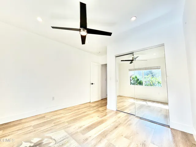a view of empty room with wooden floor and fan