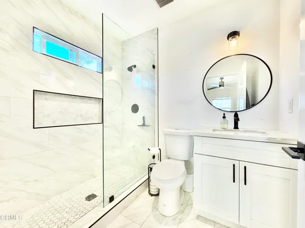 a bathroom with a sink a mirror a toilet and shower