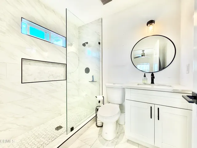 a bathroom with a sink a mirror a toilet and shower