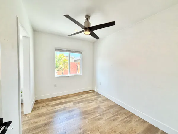 a view of empty room with wooden floor and fan