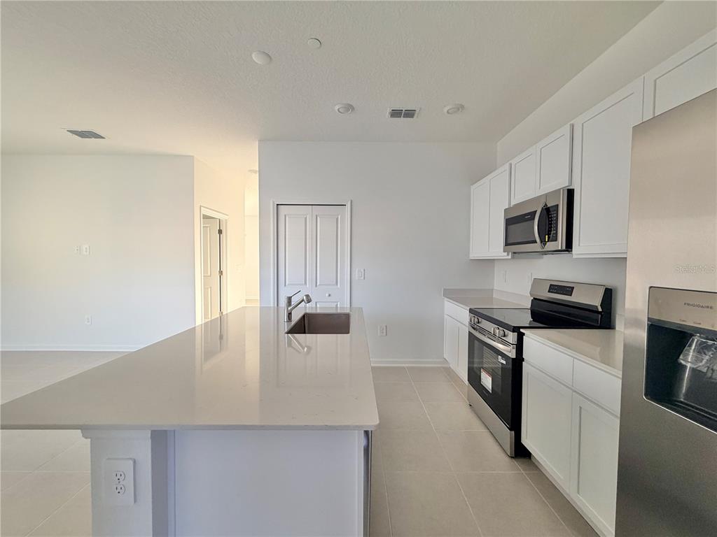 2348 Rider Rain Lane Apopka, FL 32703 - Photo 16 of 32 a kitchen with a stove a sink and a refrigerator