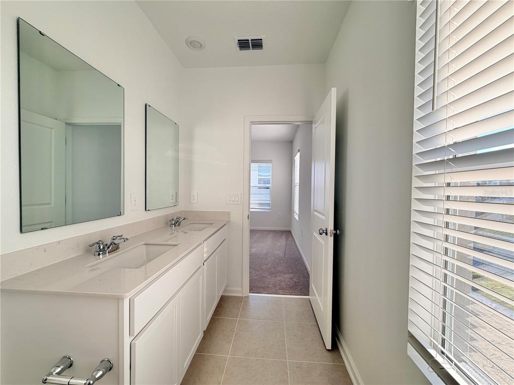 2348 Rider Rain Lane Apopka, FL 32703 - Photo 30 of 32 a en suite bathroom with a double vanity sink a mirror and a bathtub