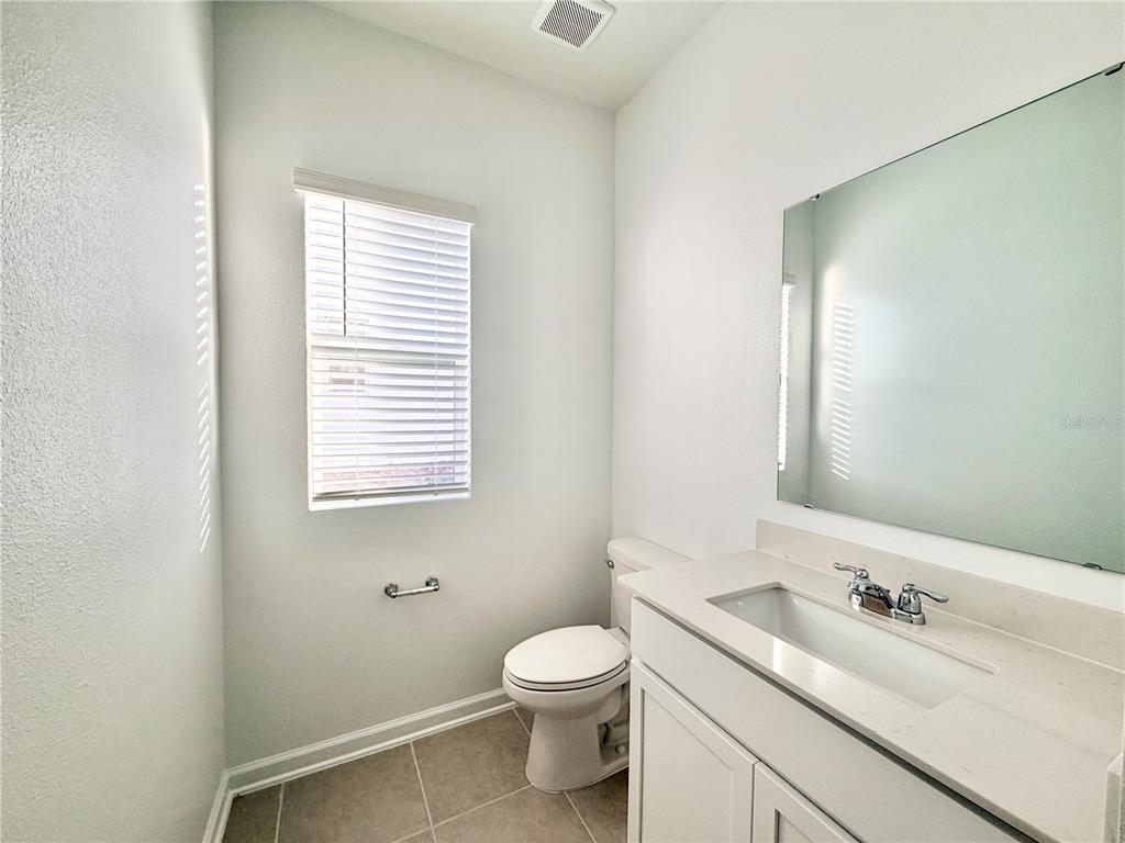 2348 Rider Rain Lane Apopka, FL 32703 - Photo 6 of 32 a bathroom with a granite countertop sink toilet a large mirror and a window