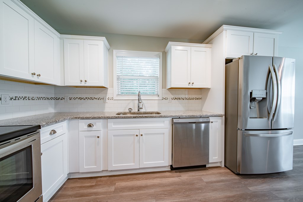 16 Maxwell Drive Fort Mitchell, AL 36856 - Photo 24 of 25 a kitchen with granite countertop white cabinets white stainless steel appliances and wooden floors
