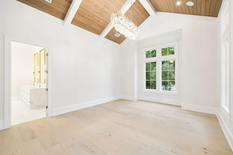 a front view of a building with a garden and trees in the background