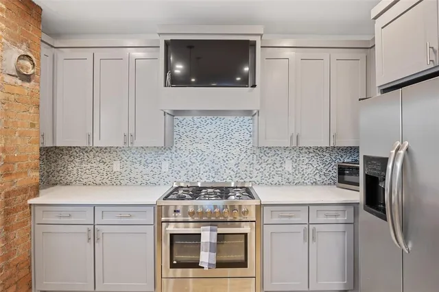 a kitchen with a refrigerator a stove top oven a sink dishwasher with a dining table and chairs