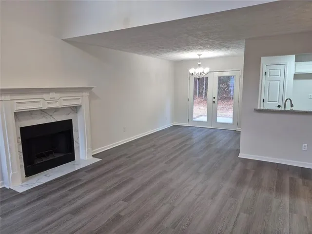 a view of an empty room with wooden floor fireplace and a window