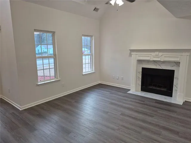 an empty room with wooden floor fireplace cabinet and windows